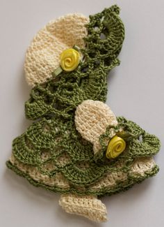 two crocheted green and white hats with yellow buttons on them sitting next to each other