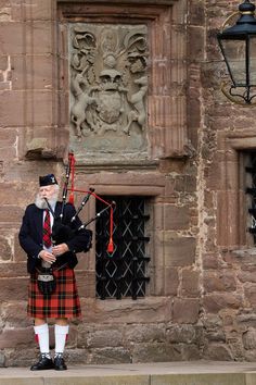 a man in a kilt playing bagpipes on the side of a building