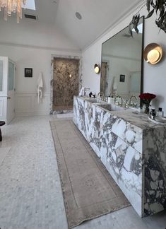 a large bathroom with marble counter tops and white walls, along with a chandelier