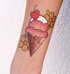 a woman's arm with an ice cream cone and cherry tattoo on the wrist