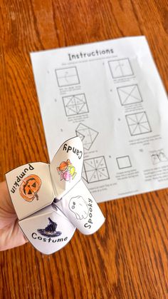 a person holding two dices in their hand on top of a wooden table next to a piece of paper