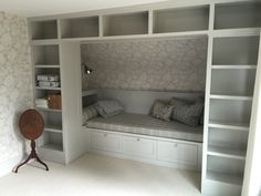 a room with built in bookshelves and a bench that has pillows on it