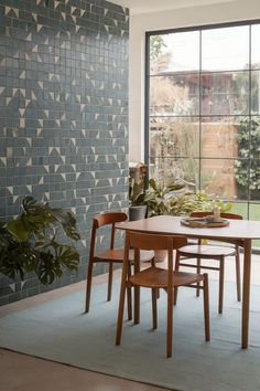 A dining room featuring a geometric blue tile accent wall with natural lighting. Nature Wallpaper Dining Room, Plant Wallpaper Dining Room, Florencecourt Wallpaper Dining Room, Banana Leaf Peel And Stick Wallpaper, Hydrangea Peel And Stick Wallpaper