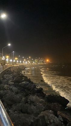 an empty street next to the ocean at night