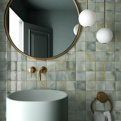 a bathroom with a round mirror above the sink and gold faucet lights on the wall