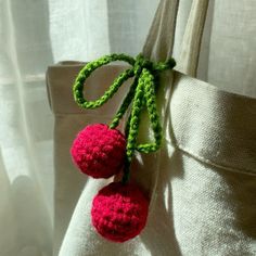 two crocheted cherries attached to a white bag