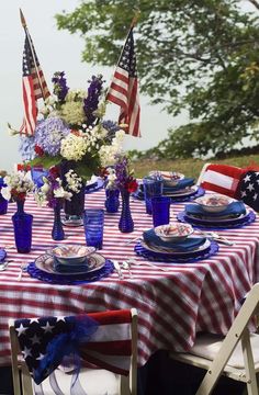 an outdoor table set with american flags and plates