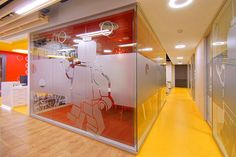 an office with yellow flooring and red glass partitions on the wall to divide it from the rest of the room