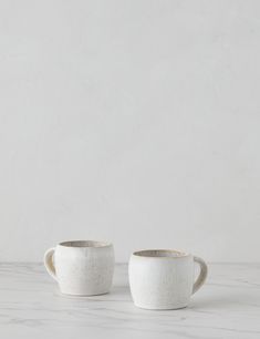 two white cups sitting on top of a table