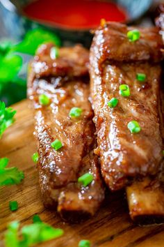 some meat is sitting on a cutting board with green garnishes around it