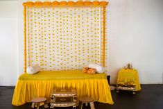 a yellow bed sitting in the middle of a room next to a table with two stools