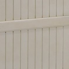 a cat sitting on top of a wooden bench next to a white wall with vertical slats