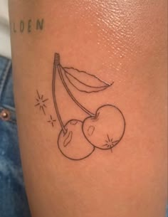 a tattoo on the leg of a woman with two cherries hanging from a branch