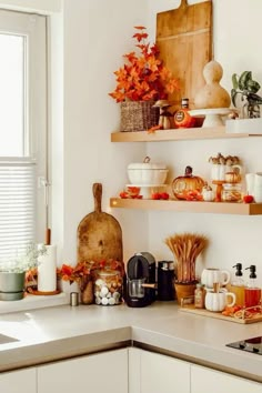 the kitchen counter is full of dishes and spices, including pumpkins on shelves above