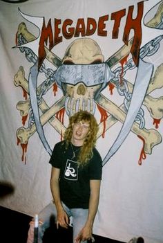 a woman standing in front of a banner that says megadeth with skulls and swords on it