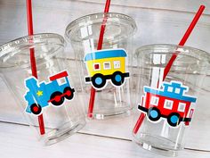 three plastic cups with red straws and colorful train stickers on the lids are sitting next to each other