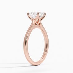 a rose gold engagement ring with a pear shaped diamond in the center, on a white background