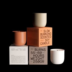 three candles are stacked on top of each other in front of a box with the words slow burning scented soy candle