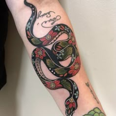 a snake tattoo on the arm with flowers and words written in cursive writing