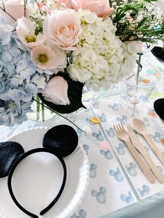 a mickey mouse head on a paper plate next to flowers and utensils in a vase