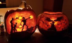 two carved pumpkins sitting on top of a table next to each other, one with people in it