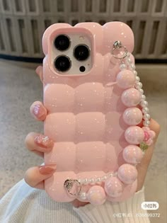 a pink iphone case with beads and pearls on the bottom, in front of a white background