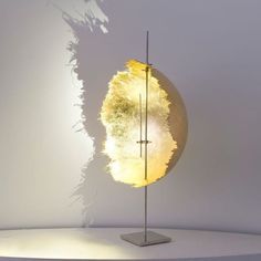 a light that is sitting on top of a metal stand in front of a white wall