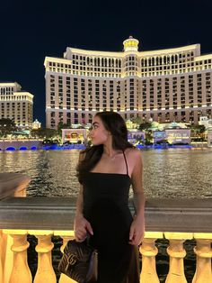 a woman standing in front of the las vegas hotel and casino at night with her hand on her hip