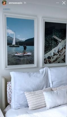 there are two pictures hanging on the wall above a bed with white sheets and pillows