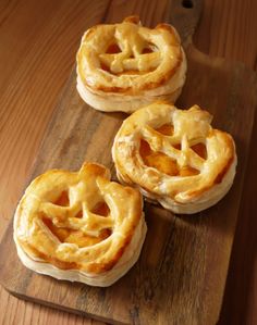 three small pies sitting on top of a wooden cutting board