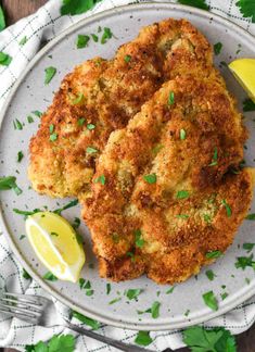 two crab cakes on a plate with lemon wedges and parsley garnish