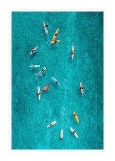 an aerial view of several small boats in the blue water, with one yellow and one red