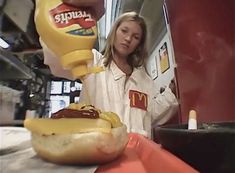 a woman is pouring ketchup on a hot dog at a fast food restaurant