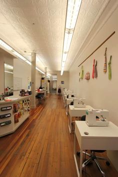 an empty room with several sewing machines on the wall and wooden floors in front of it