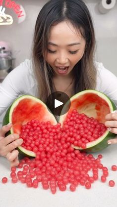 a woman holding a watermelon in front of her face and making a heart shape