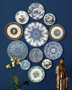 there are many plates on the wall with buddha statue next to it and one is holding a flower