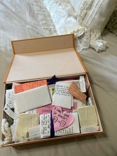 an open box filled with lots of different types of paper and tags on top of a bed