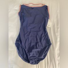 a woman's blue swimsuit laying on top of a white sheeted bed