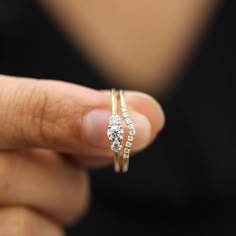 a woman is holding a ring with two diamonds on it's sides and the other side has a curved band