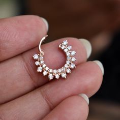 a close up of a person holding a small earring in their left hand and wearing a ring with flowers on it