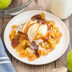 a white plate topped with an ice cream sundae next to two green apples and a glass of milk