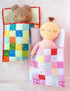 two stuffed animals laying next to each other on top of a bed covered in quilts