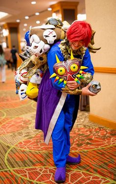 a man with red hair and blue outfit carrying stuffed animals on his back while walking down a hallway