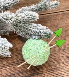 a green ball of yarn sitting on top of a wooden table next to some branches