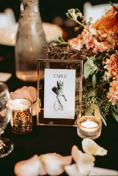 the table is set with candles, flowers and an empty card for someone to write their name