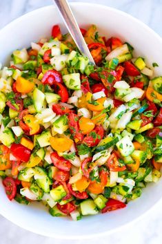 a white bowl filled with cucumber and tomato salad