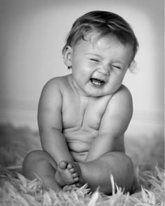 a black and white photo of a baby crying on the floor with his mouth wide open