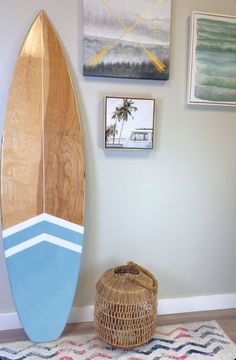 a surfboard leaning up against the wall next to a basket with a palm tree on it