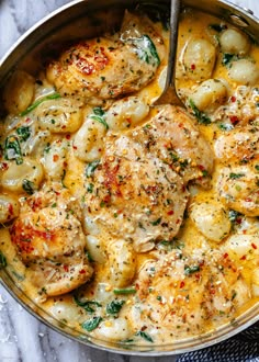 a pan filled with chicken and potatoes covered in gravy on top of a table