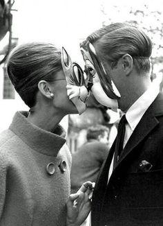 a man and woman kissing each other in front of an old camera with goggles on their mouths